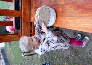 Dziewczynka w kuchni błotnej z garnkiem wypełnionym piaskiem